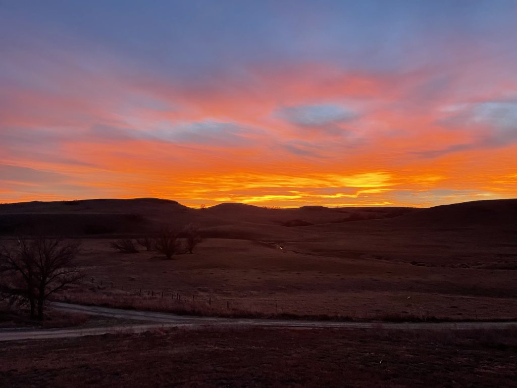 Colorful sunset over a butte with driveway.  